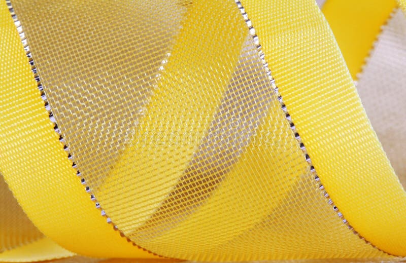 Macro shot of a yellow ribbon with golden textile background. Macro shot of a yellow ribbon with golden textile background