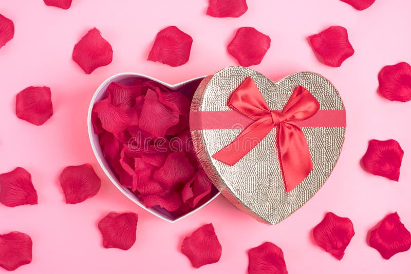 Giftdoos in de vorm van een hart met roze bloemblaadjes binnen op dag het de als achtergrond concept van roze Gelukkig Valentine royalty-vrije stock fotografie Giftdoos in de vorm van een hart met roze bloemblaadjes binnen op dag het de als achtergrond concept van roze Gelukkig Valentine royalty-vrije stock fotografie