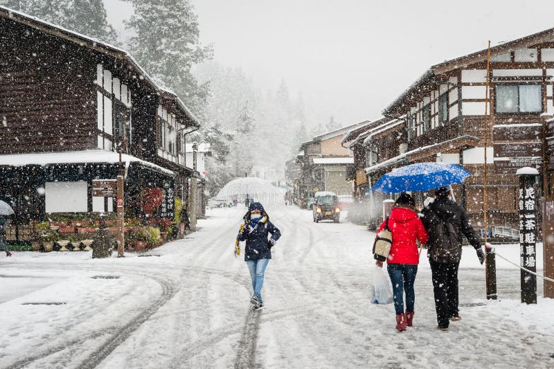 Female tourist holding transparent umbrella and walking on the street with background of Shirakawa-go village. the snow is heavy