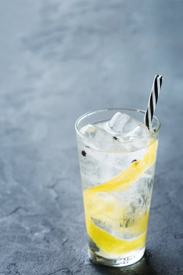 Food and drink, holidays party concept. Gin and tonic alcohol cocktail drink with ice and lemon zest in a glass on a grunge dark table. Copy space background. Food and drink, holidays party concept. Gin and tonic alcohol cocktail drink with ice and lemon zest in a glass on a grunge dark table. Copy space background