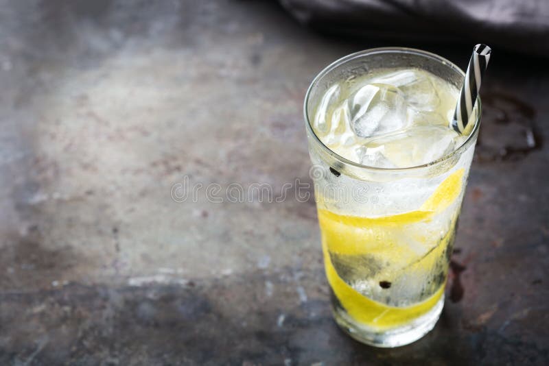 Food and drink, holidays party concept. Gin and tonic alcohol cocktail drink with ice and lemon zest in a glass on a grunge dark table. Copy space background. Food and drink, holidays party concept. Gin and tonic alcohol cocktail drink with ice and lemon zest in a glass on a grunge dark table. Copy space background