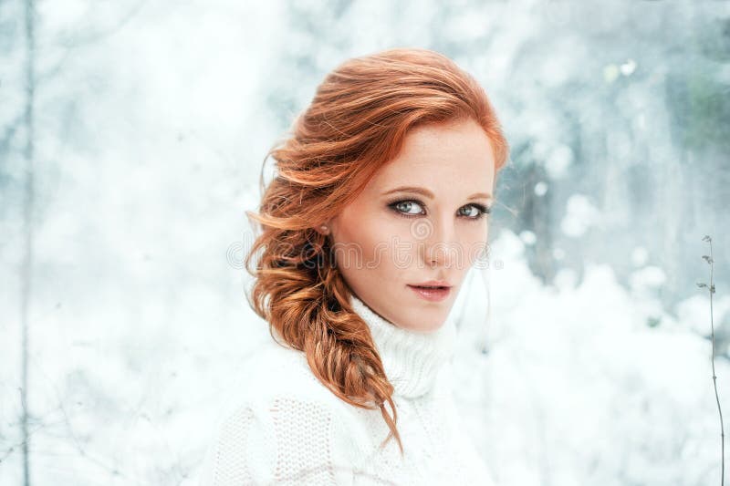 Ginger happy female in white sweater in winter forest. Snow december in park. Portrait. Christmas cute time.