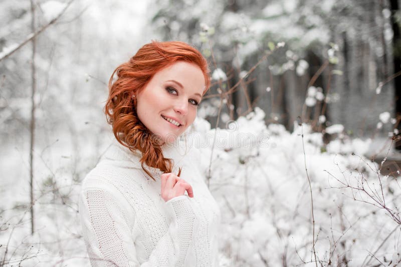Ginger happy girl in white sweater in winter forest. Snow december in park. Portrait. Christmas cute time. stock photo Ginger happy girl in white sweater in winter forest. Snow december in park. Portrait. Christmas cute time. stock photo
