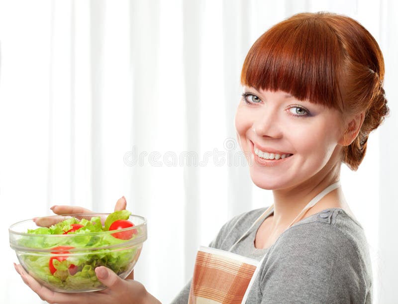 Ginger housewife holding glass plate with salad