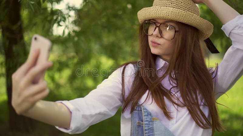 Ginger student smiling and making selfie in park on summer day