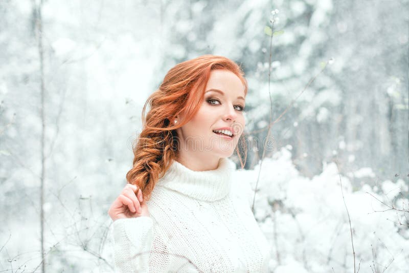 Ginger sweet girl in white sweater in winter forest. Snow december in park. Portrait. Christmas cute time.