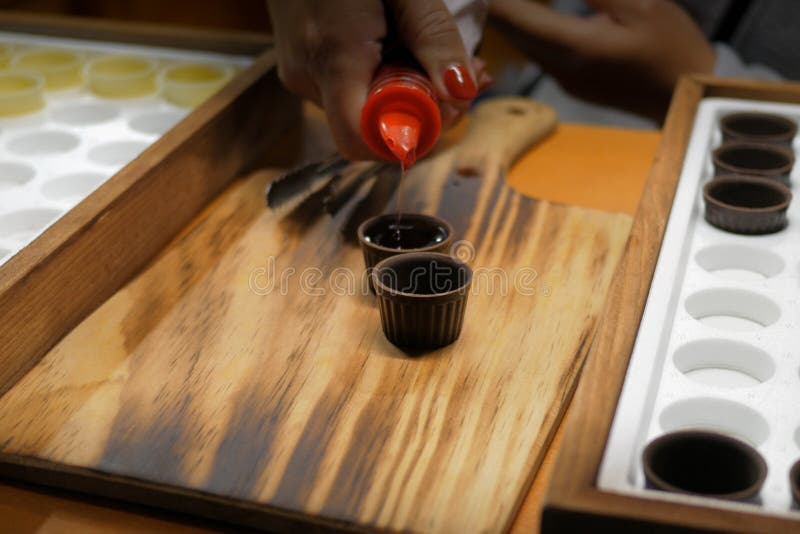 Ginja / Ginjinha cherry liqueur drink being poured into chocolate cups on Wooden background. Traditional Portuguese drink