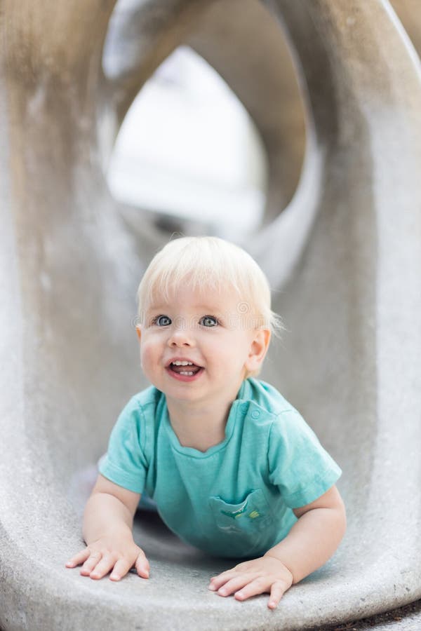 Giocare all'aperto. giochi per bambini in giardino scolastico o d'asilo. bambino attivo su scivolo di pietra immagini stock libere da diritti