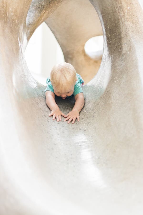 Giocare all'aperto. giochi per bambini in giardino scolastico o d'asilo. bambino attivo su scivolo di pietra fotografia stock