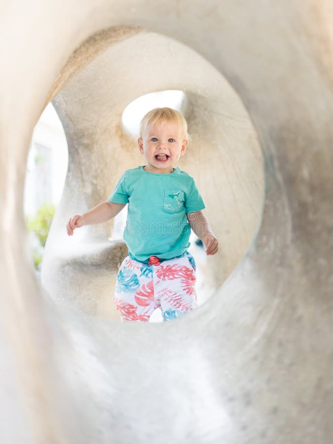 Giocare all'aperto. giochi per bambini in giardino scolastico o d'asilo. bambino attivo su scivolo di pietra fotografia stock