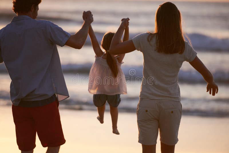 Giocare a bambini e genitori tenendosi per mano sulla spiaggia per divertimento durante le vacanze estive e collegandosi insieme. immagine stock