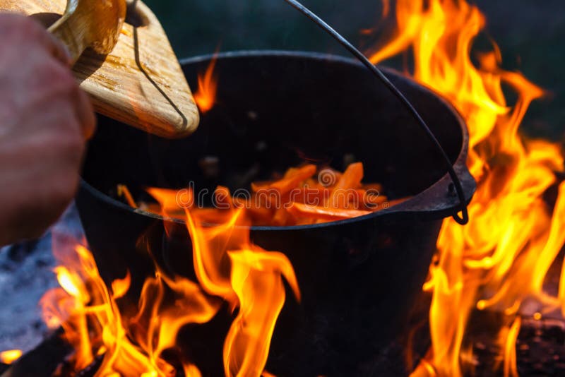 Giocatore di bocce turistico con alimento sul falò, cucinante nell'aumento, attività all'aperto Preparazione di pilaf immagini stock libere da diritti Giocatore di bocce turistico con alimento sul falò, cucinante nell'aumento, attività all'aperto Preparazione di pilaf immagini stock libere da diritti