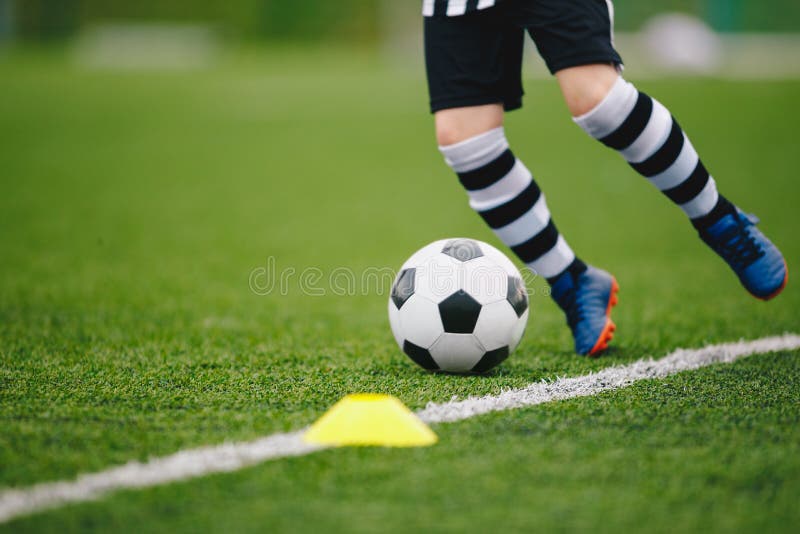 Giocatore di calcio di dettaglio che calza la palla al margine del passo. calciatore in una partita