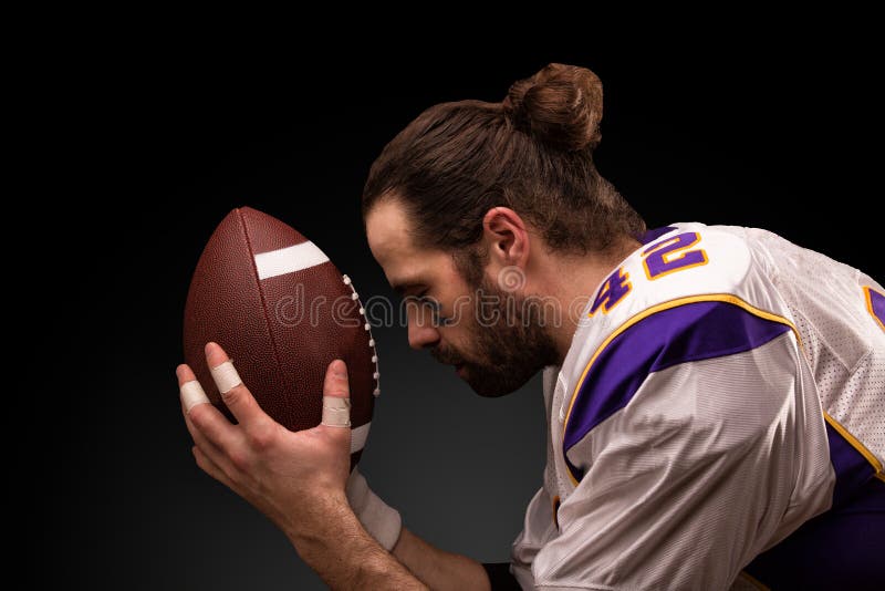 Giocatore di football americano con una palla sul momento da pregare prima del gioco immagine stock Giocatore di football americano con una palla sul momento da pregare prima del gioco immagine stock