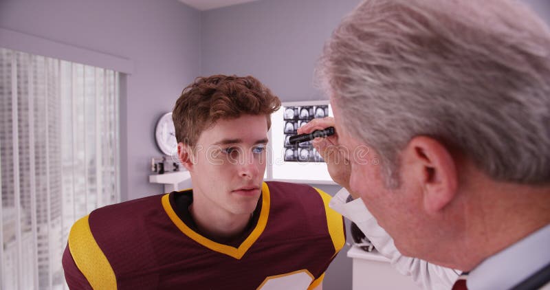 giocatore di football americano d'esame Mezzo vecchio di medico dopo lo sbattimento immagini stock giocatore di football americano d'esame Mezzo vecchio di medico dopo lo sbattimento immagini stock
