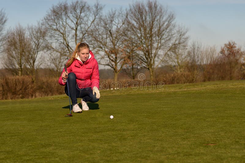 Giocatore di golf femminile che allinea un tiro in buca fotografie stock libere da diritti Giocatore di golf femminile che allinea un tiro in buca fotografie stock libere da diritti