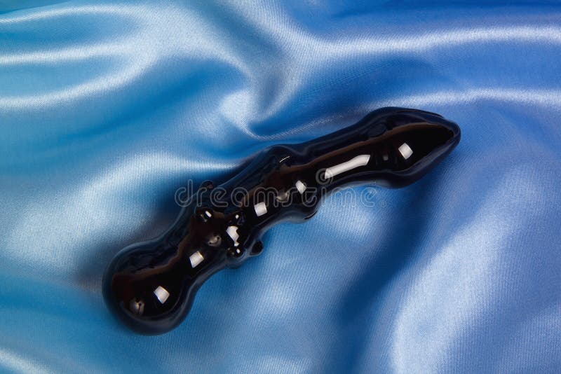 Giocattolo nero del sesso della spina di estremità fatto di vetro sul blu fotografie stock Giocattolo nero del sesso della spina di estremità fatto di vetro sul blu fotografie stock