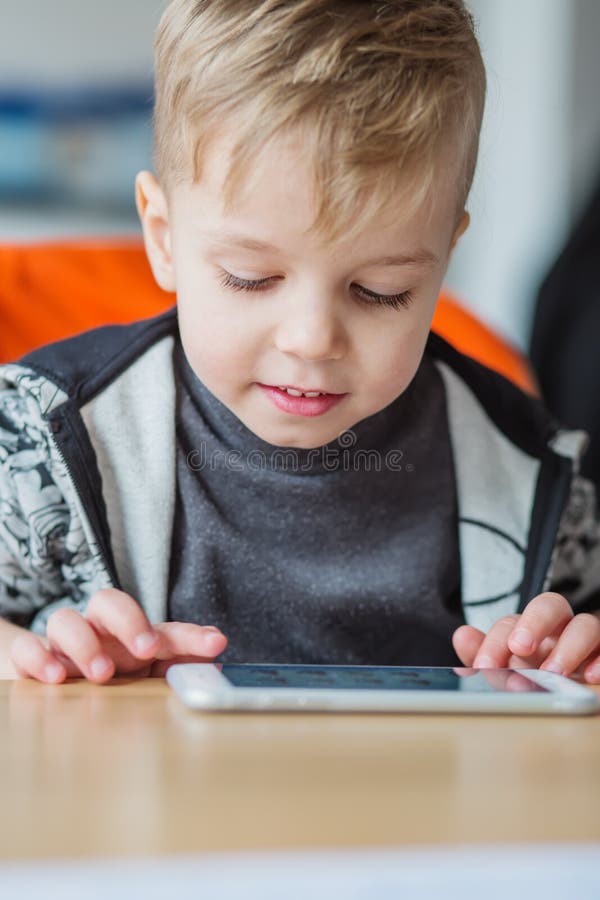 Giochi caucasici sorridenti adorabili del bambino con lo Smart Phone fotografia stock libera da diritti