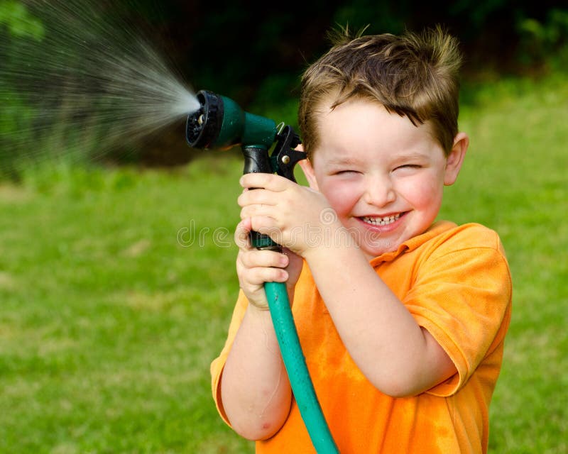 Giochi da bambini con il tubo flessibile dell'acqua all'aperto immagini stock libere da diritti Giochi da bambini con il tubo flessibile dell'acqua all'aperto immagini stock libere da diritti