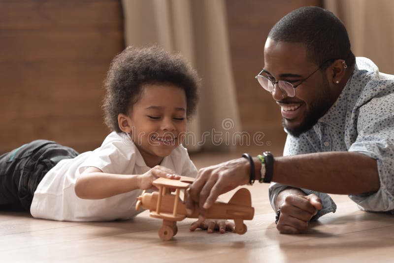 Gioco africano felice del ragazzo del bambino e del papà con l'aereo del giocattolo