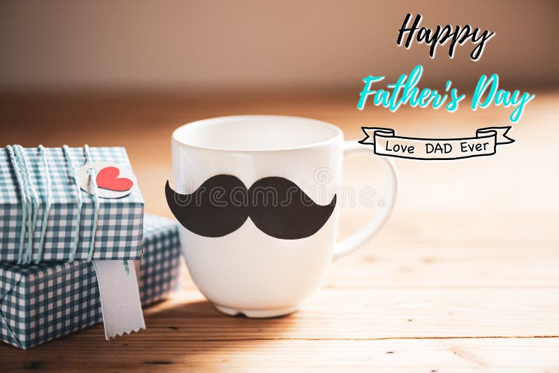 Happy fathers day concept. Gift box, mustache and coffee cup with paper red heart tag on wooden table background. Happy fathers day concept. Gift box, mustache and coffee cup with paper red heart tag on wooden table background.