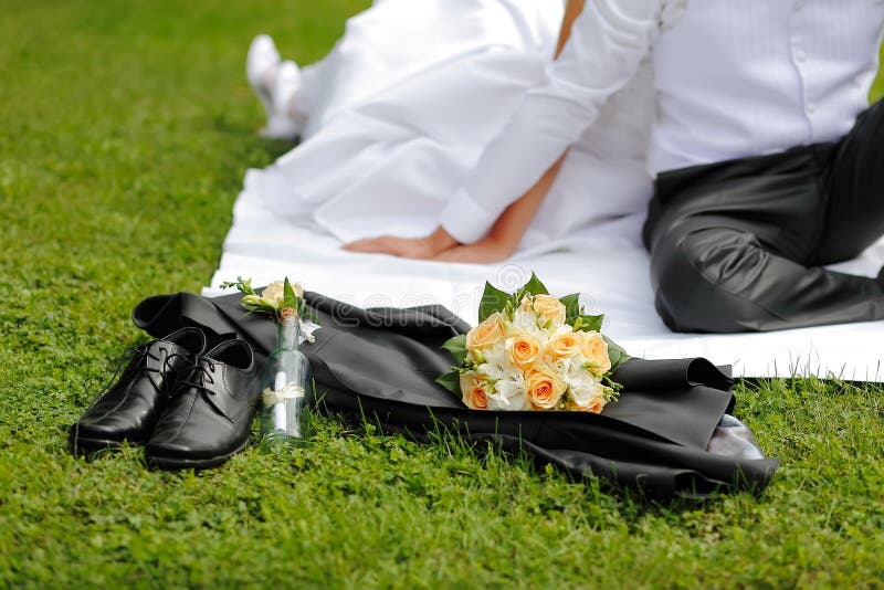 Wedding groom's shoes, jacket, bouquet, a reference in a bottle in the background the bride and groom hands. Wedding groom's shoes, jacket, bouquet, a reference in a bottle in the background the bride and groom hands