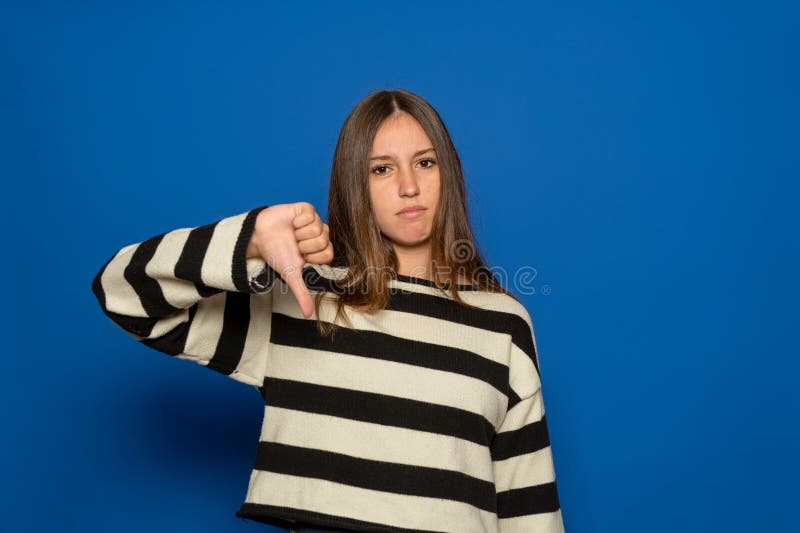 Giovane adolescente ispanico con un maglione a strisce che sembra infelice e arrabbiato e che mostra rifiuto e negatività immagine stock