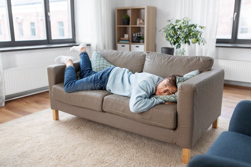 people, boredom and depression concept - bored or lazy young man lying on sofa at home. people, boredom and depression concept - bored or lazy young man lying on sofa at home