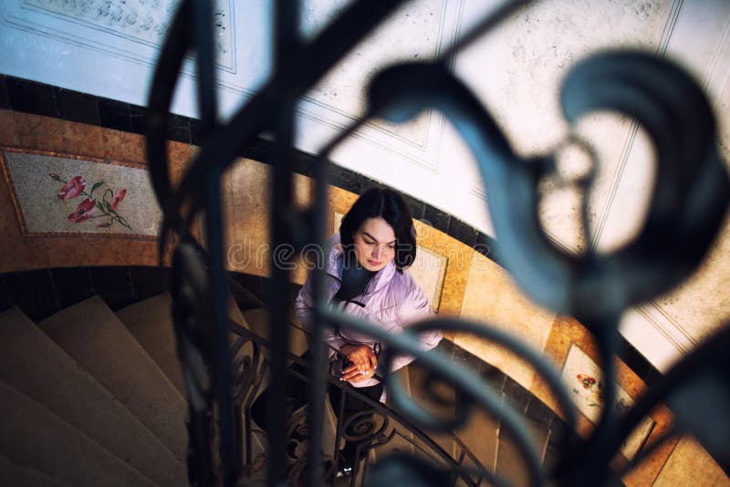 Giovane bella condizione della donna sulla vecchia scala a chiocciola rotonda fotografia stock libera da diritti Giovane bella condizione della donna sulla vecchia scala a chiocciola rotonda fotografia stock libera da diritti