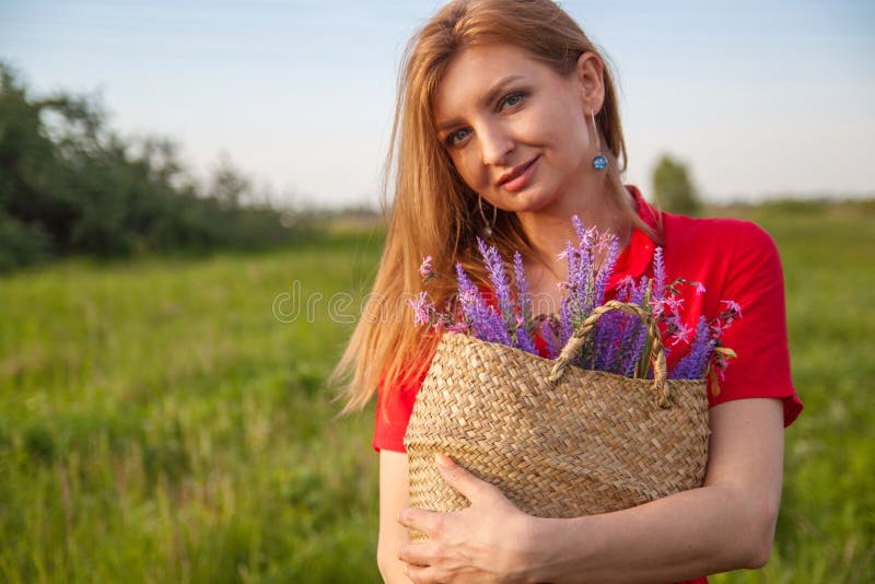 Giovane bella donna bionda che smilling con i fiori in natura di estate fotografie stock Giovane bella donna bionda che smilling con i fiori in natura di estate fotografie stock