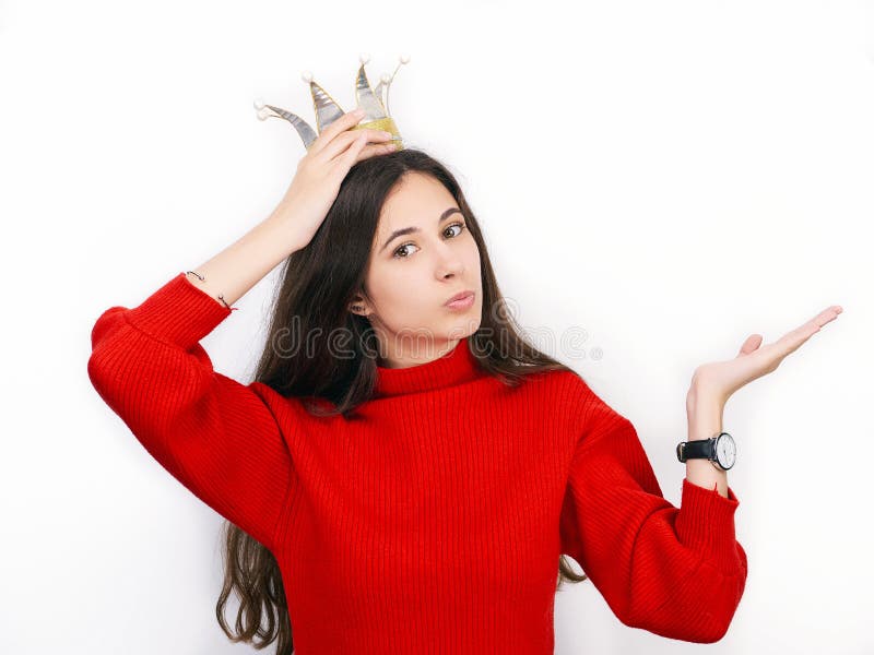 Giovane bella donna castana in maglione rosso e corona diy che giocano principessa contro il fondo bianco fotografia stock libera da diritti Giovane bella donna castana in maglione rosso e corona diy che giocano principessa contro il fondo bianco fotografia stock libera da diritti