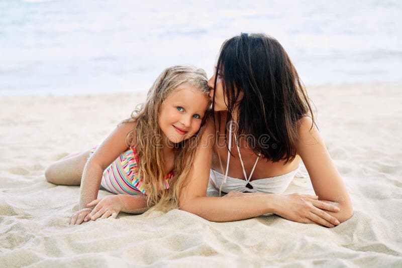 Giovane bella donna che bacia la sua piccola figlia per rilassarsi sulla spiaggia tropicale nelle vacanze estive fotografia stock Giovane bella donna che bacia la sua piccola figlia per rilassarsi sulla spiaggia tropicale nelle vacanze estive fotografia stock