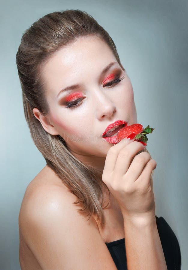Giovane bella donna che mangia fragola fotografia stock Giovane bella donna che mangia fragola fotografia stock