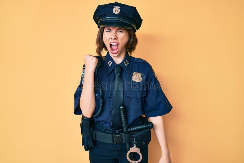 Giovane bella donna con addosso l'uniforme della polizia arrabbiata e arrabbiata sollevando il pugno frustrata e furiosa urlando con rabbia. rabbia e concetto aggressivo