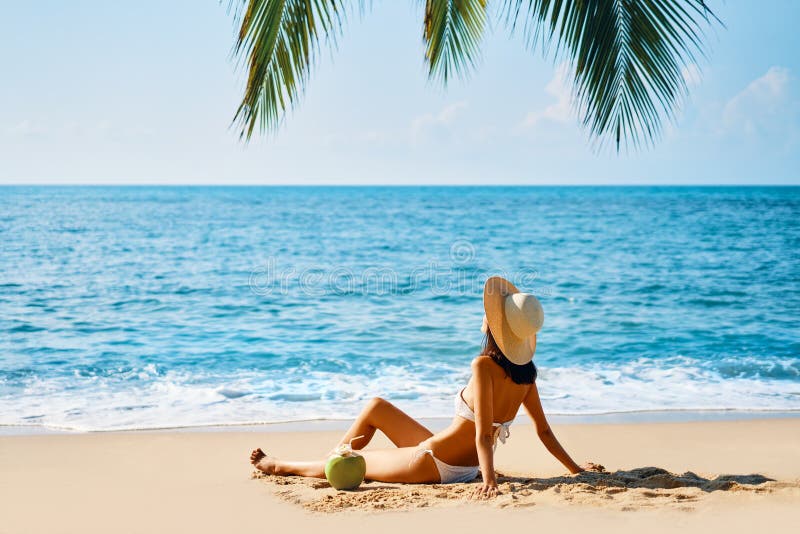 Giovane bella donna prendere il sole e rilassarsi seduta da solo sulla spiaggia tropicale fotografie stock libere da diritti Giovane bella donna prendere il sole e rilassarsi seduta da solo sulla spiaggia tropicale fotografie stock libere da diritti