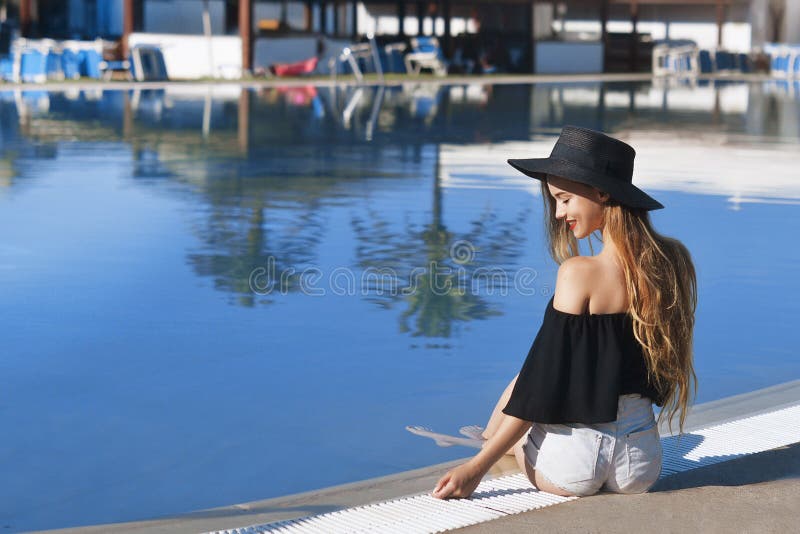 Giovane bella pelle del velluto di sorriso della ragazza, labbra rosse, costume da bagno nero che posa nello stagno in acqua blu, fotografia stock Giovane bella pelle del velluto di sorriso della ragazza, labbra rosse, costume da bagno nero che posa nello stagno in acqua blu, fotografia stock