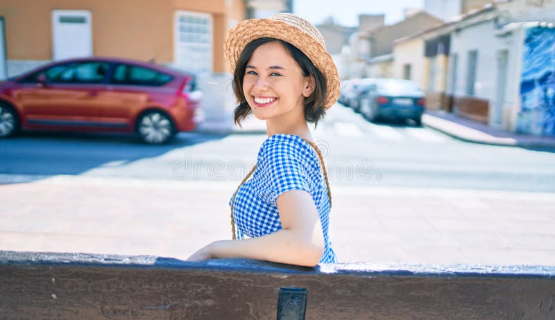 Giovane bella ragazza sorridente felice seduta sulla panchina in città fotografia stock