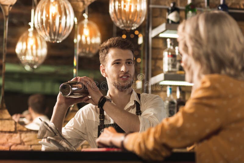 Giovane bello che chiacchiera mentre facendo cocktail fotografia stock libera da diritti Giovane bello che chiacchiera mentre facendo cocktail fotografia stock libera da diritti