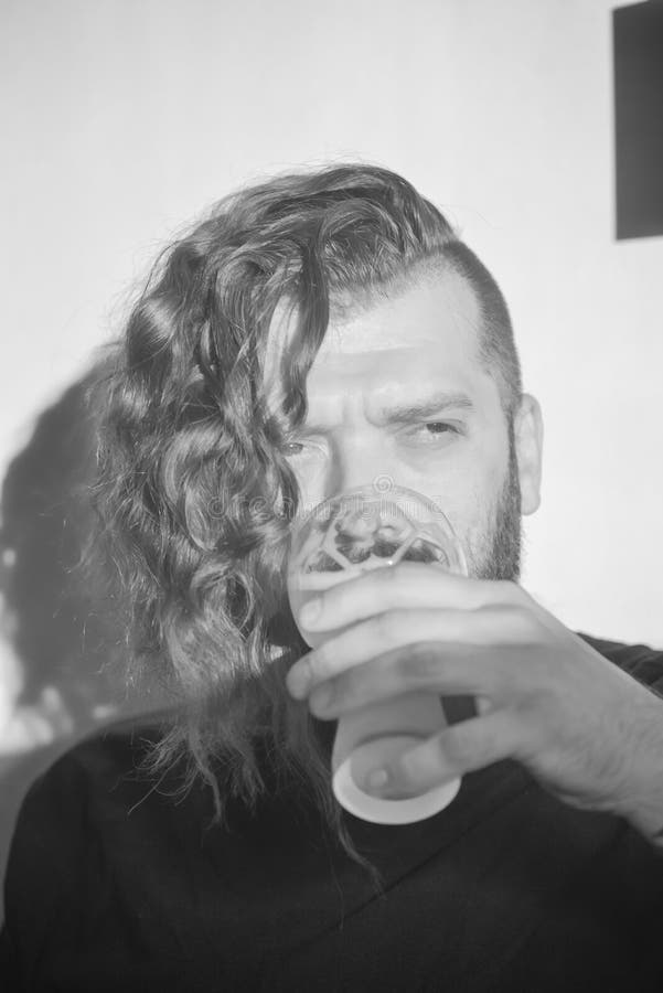 Giovane bello con capelli ricci lunghi e una barba Castana brutale dell'uomo in una maglietta nera e con un taglio di capelli all fotografia stock Giovane bello con capelli ricci lunghi e una barba Castana brutale dell'uomo in una maglietta nera e con un taglio di capelli all fotografia stock