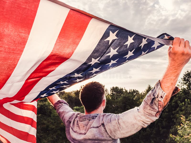 Giovane bello e che tiene una bandiera americana fotografie stock Giovane bello e che tiene una bandiera americana fotografie stock