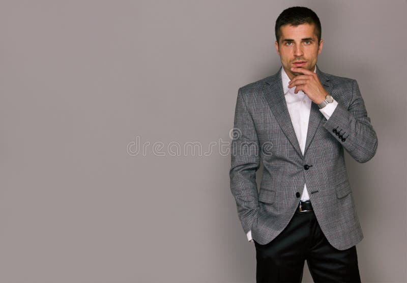 Giovane bello elegante in un rivestimento grigio fotografie stock libere da diritti Giovane bello elegante in un rivestimento grigio fotografie stock libere da diritti