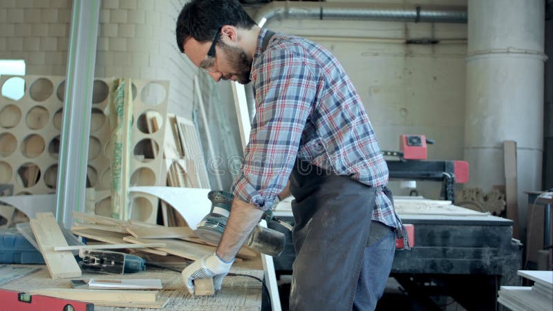 Giovane carpentiere che lavora con la macchina elettrica nell'officina immagine stock Giovane carpentiere che lavora con la macchina elettrica nell'officina immagine stock