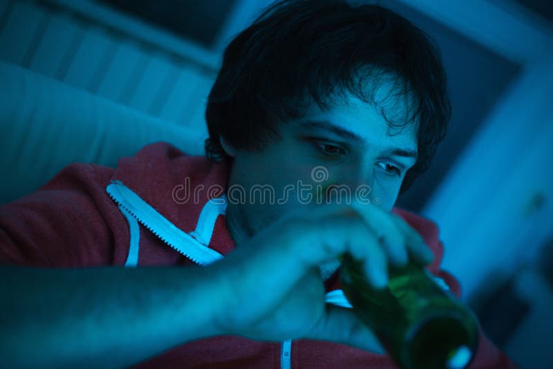 Giovane che guarda TV e che beve birra fotografia stock libera da diritti Giovane che guarda TV e che beve birra fotografia stock libera da diritti