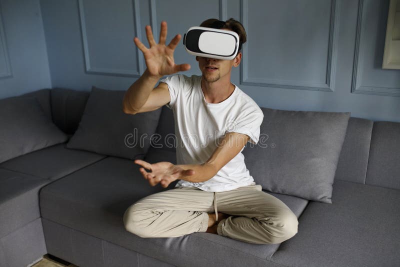 Giovane che indossa occhiali di realtà virtuale nell'interno del coworking moderno seduto sul divano. smartphone con cuffia vr 3d immagini stock libere da diritti