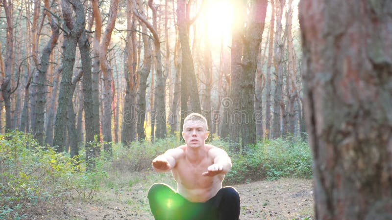 Giovane che lavora in una bella foresta soleggiata. sportivo che fa squat al tramonto. addestramento di atleta