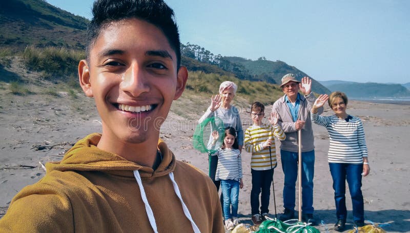 Giovane che prende selfie al gruppo di volontari dopo la pulizia della spiaggia immagine stock Giovane che prende selfie al gruppo di volontari dopo la pulizia della spiaggia immagine stock
