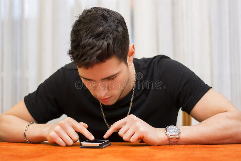 Giovane che scrive un messaggio di testo a macchina sul suo telefono fotografia stock libera da diritti Giovane che scrive un messaggio di testo a macchina sul suo telefono fotografia stock libera da diritti