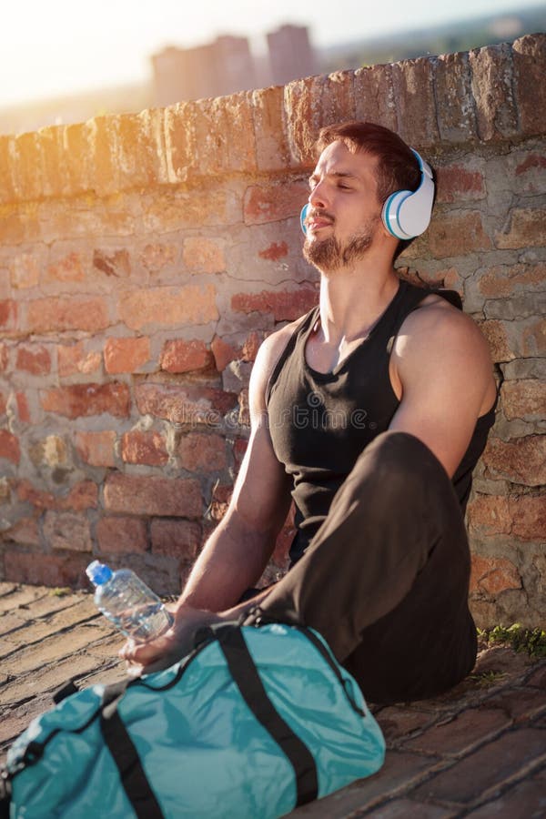 Giovane che si rilassa e che ascolta la musica dopo un allenamento duro fotografia stock Giovane che si rilassa e che ascolta la musica dopo un allenamento duro fotografia stock
