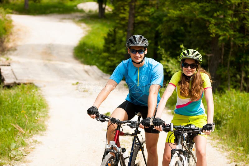Giovane ciclismo ATTIVO delle coppie su un sentiero forestale in montagna su uno spr