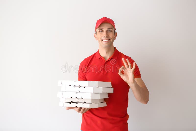 Giovane con i contenitori di pizza che mostrano segno GIUSTO su fondo leggero Servizio di distribuzione dell'alimento fotografie stock Giovane con i contenitori di pizza che mostrano segno GIUSTO su fondo leggero Servizio di distribuzione dell'alimento fotografie stock